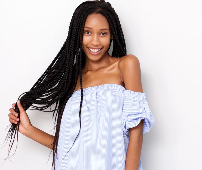 Portrait of beautiful african american woman with braided hair smiling against white background